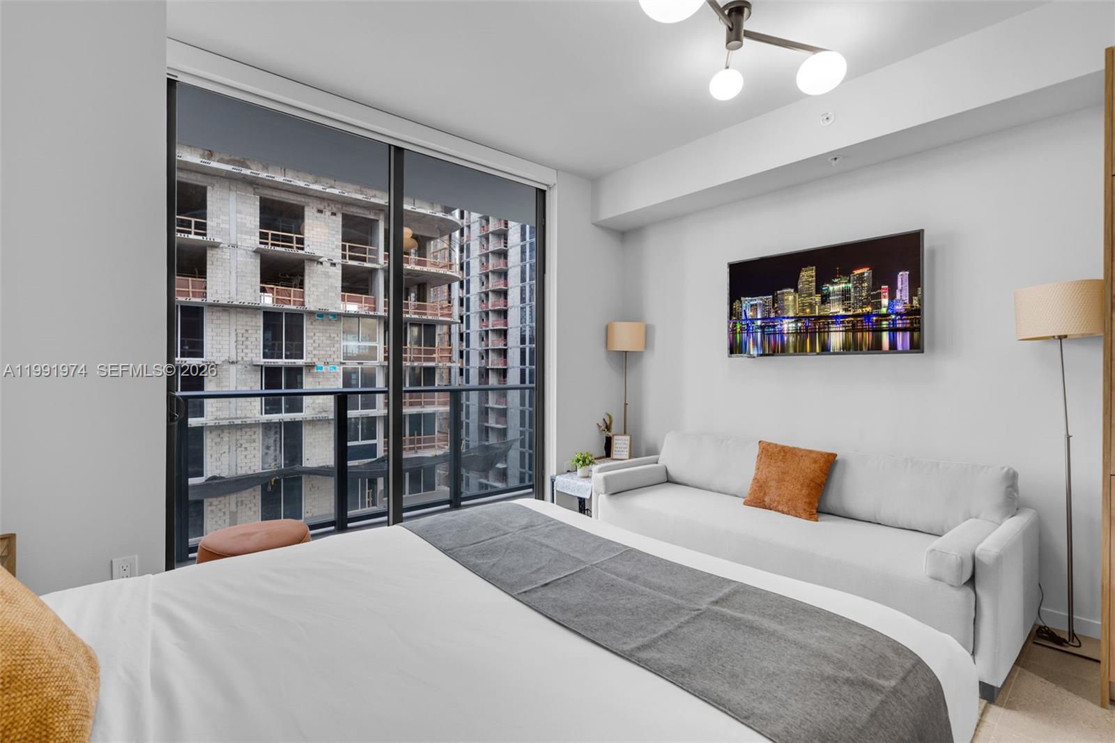 11 Northeast 6th Street, Unit 2808 Miami, FL 33132 - Photo 11 of 57 a bedroom with a large bed and a chandelier