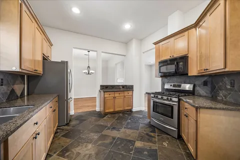 a kitchen with stainless steel appliances granite countertop a stove a sink and a microwave