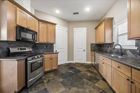 a kitchen with stainless steel appliances granite countertop a stove a sink and a microwave
