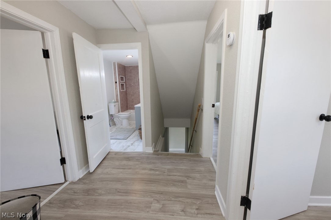 416 5th Street Chester, WV 26034 - Photo 17 of 24 Hallway with wood-finish flooring, white paneled doors with black hardware, and light neutral wall paint