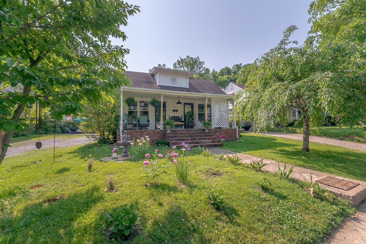 a view of house with a big yard and potted plants