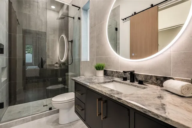 a bathroom with a granite countertop sink a toilet and shower