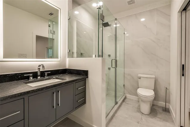 a bathroom with a granite countertop sink a toilet and a mirror