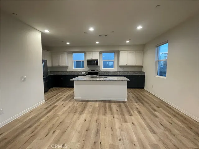 a kitchen with granite countertop a refrigerator and cabinets