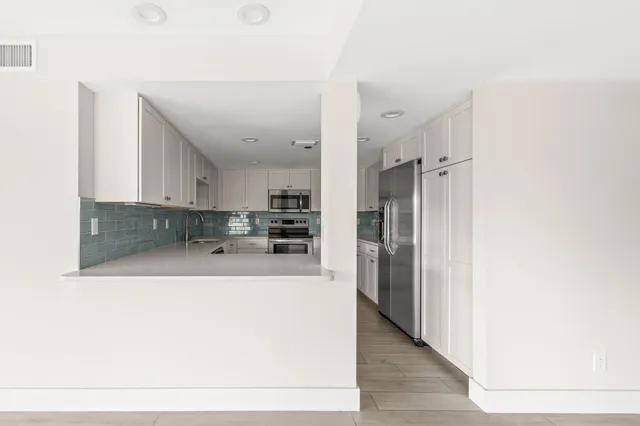 a large white kitchen with a refrigerator and a sink