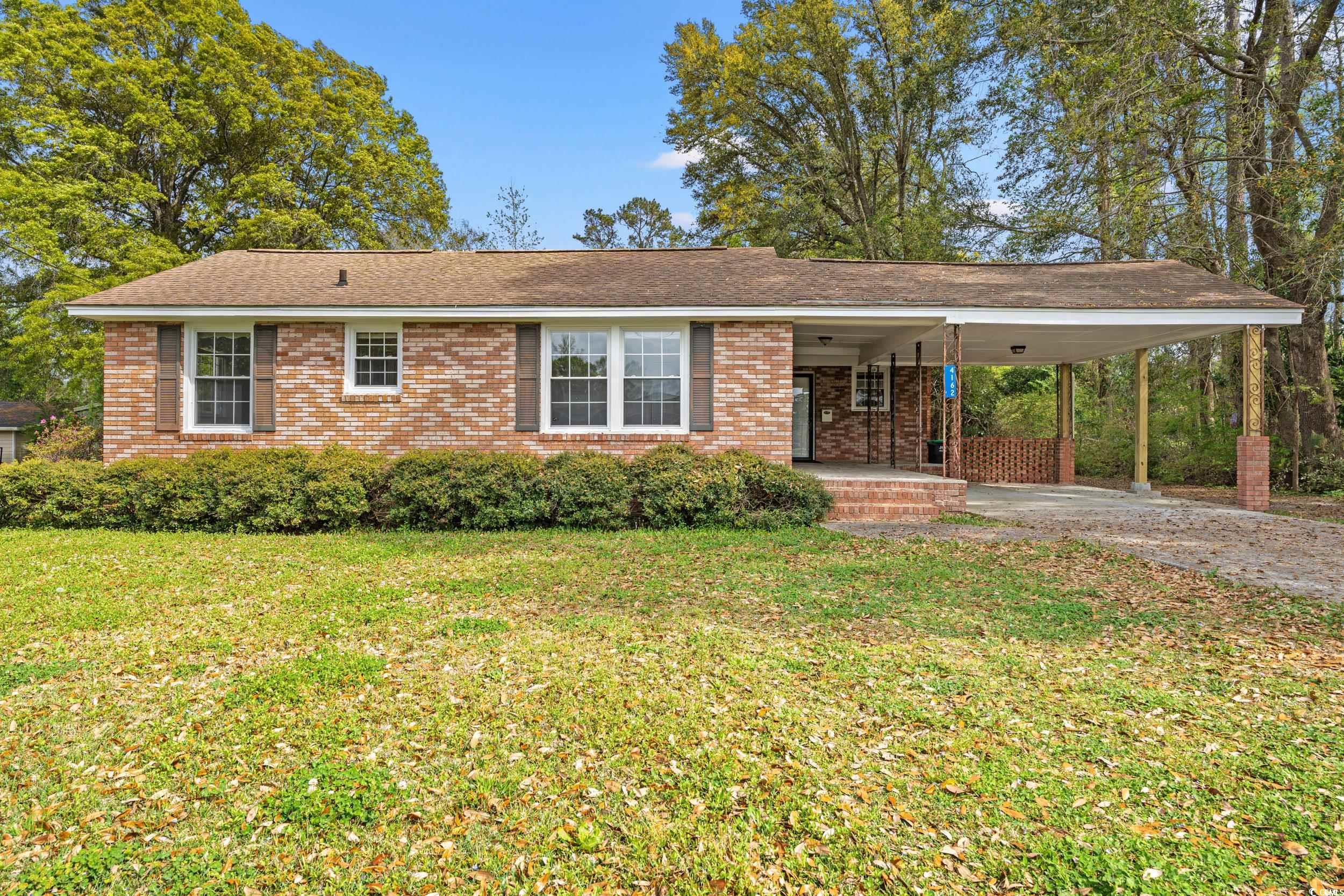View of front of property with a carport, brick si