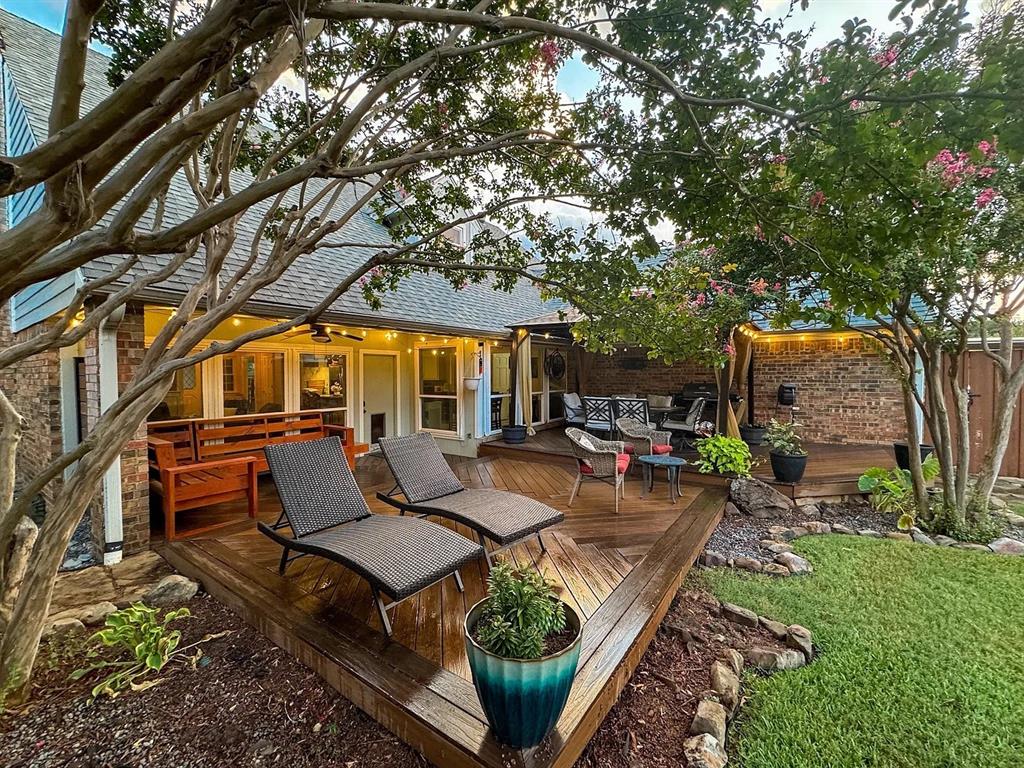 9911 Silver Creek Road Dallas, TX 75243 - Photo 27 of 28 Expansive wood-finish deck with integrated lighting, surrounded by mature trees and manicured landscaping