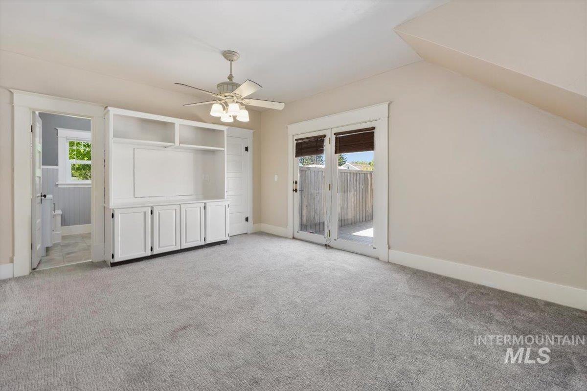813 7th Street Rupert, ID 83350 - Photo 26 of 48 Spacious room featuring light gray carpet, a built-in entertainment center with shelving and cabinet storage, and a ceiling fan with integrated lighting
