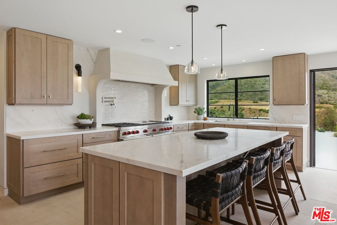 6326 Trancas Canyon Road Malibu, CA 90265 - Photo 17 of 53 a kitchen with a stove a refrigerator a sink a dining table and chairs
