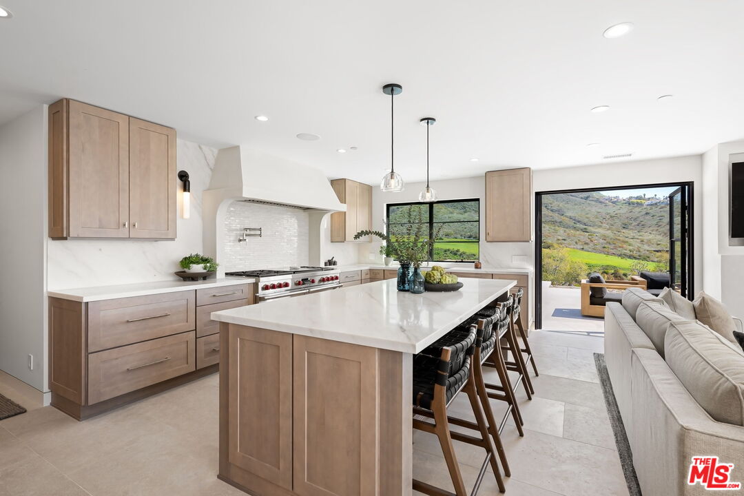6326 Trancas Canyon Road Malibu, CA 90265 - Photo 21 of 53 a kitchen with stainless steel appliances kitchen island a large window and white cabinets