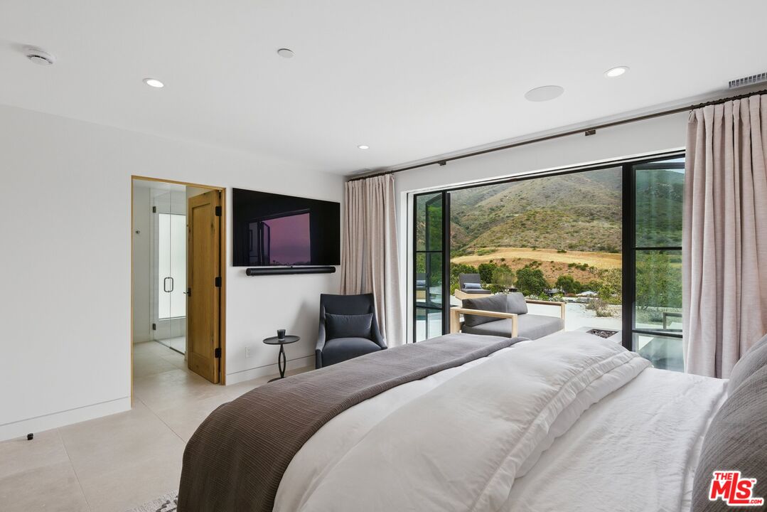 6326 Trancas Canyon Road Malibu, CA 90265 - Photo 26 of 53 a bedroom with a large bed and a flat tv screen on dresser