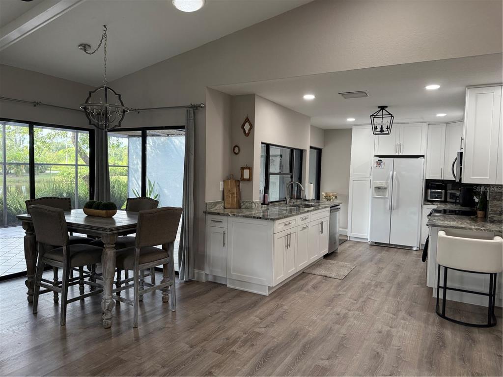 35 Pinewinds Boulevard Oldsmar, FL 34677 - Photo 11 of 36 a kitchen with stainless steel appliances kitchen island granite countertop a stove a refrigerator a microwave a dining table and chairs with wooden floor