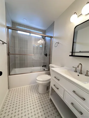 a bathroom with a toilet a sink a mirror a bathtub and shower