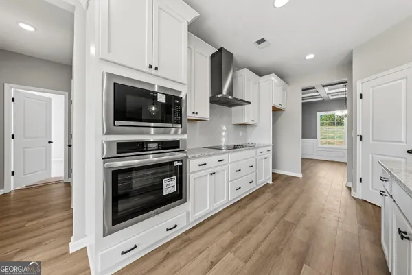 a kitchen with stainless steel appliances white cabinets a stove a sink and a refrigerator