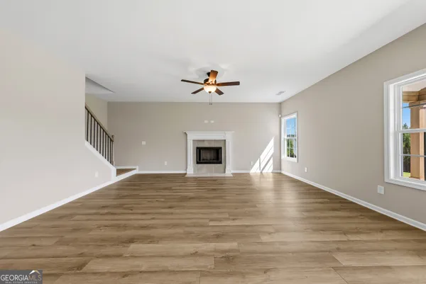 a view of an empty room with window and wooden floor