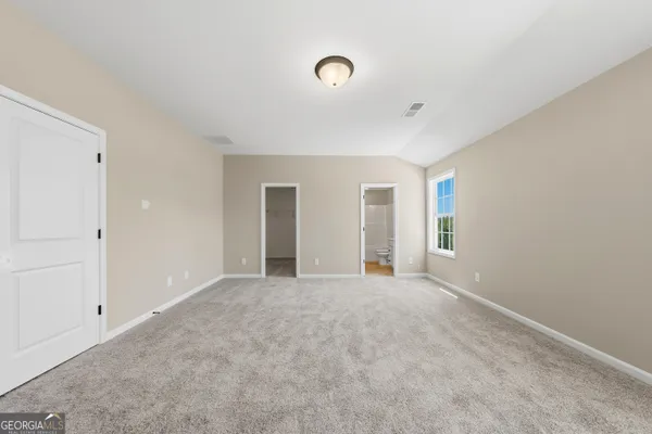 a view of an empty room with window and closet area