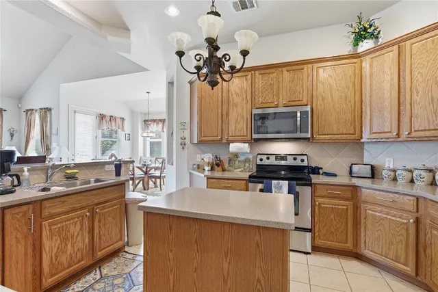 a kitchen with stainless steel appliances granite countertop a sink a stove top oven a chimney and cabinets