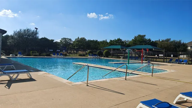 a view of a swimming pool with a bench and trees in the background