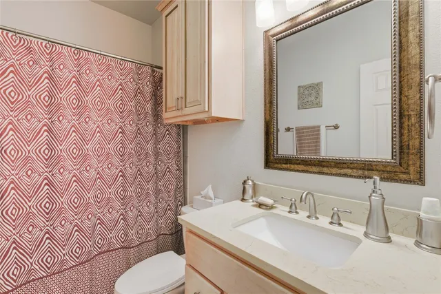 a bathroom with a granite countertop toilet sink and mirror
