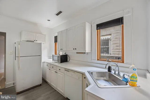 a kitchen with refrigerator a sink and white cabinets