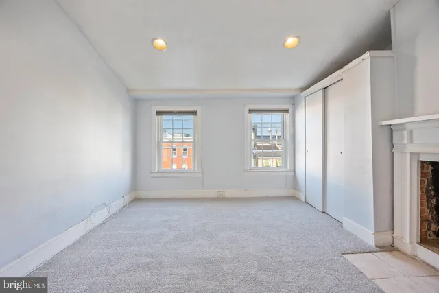 an empty room with windows and fireplace