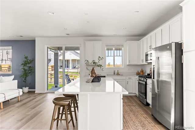 a kitchen with a refrigerator a stove and a dining table with wooden floor