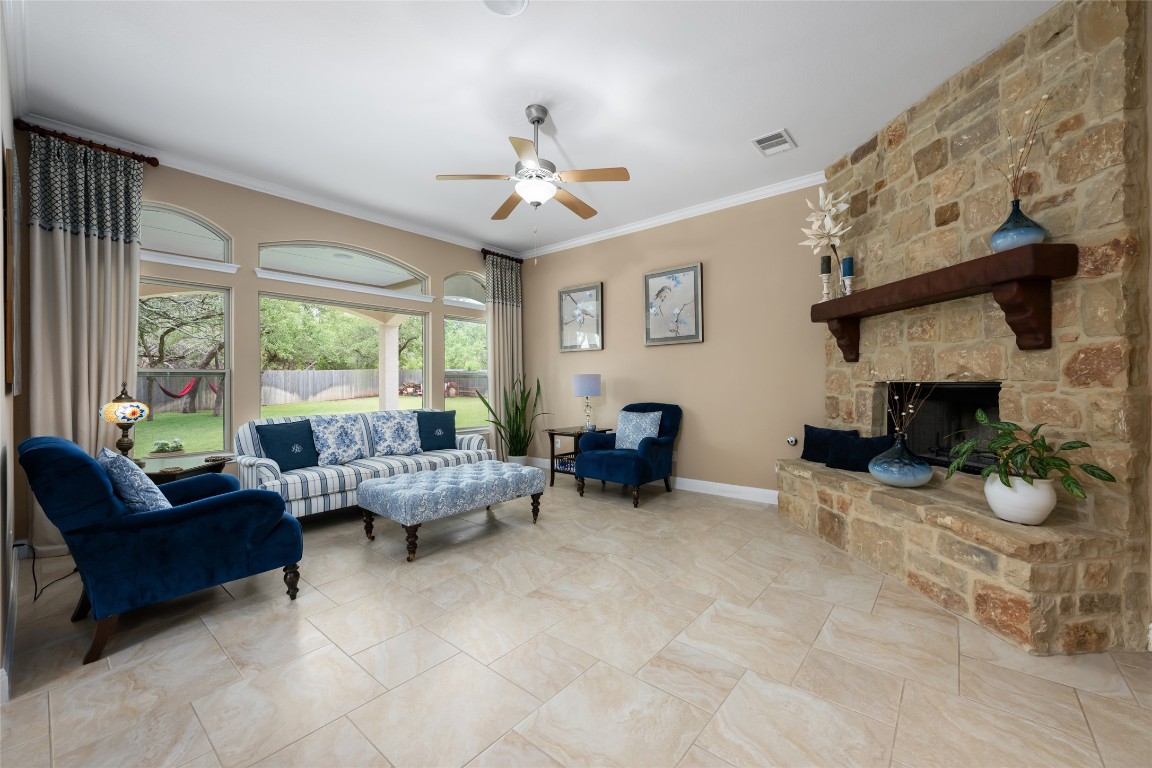399 Whispering Wind Way Austin, TX 78737 - Photo 13 of 40 Living area with ceiling fan, ornamental molding, and a fireplace