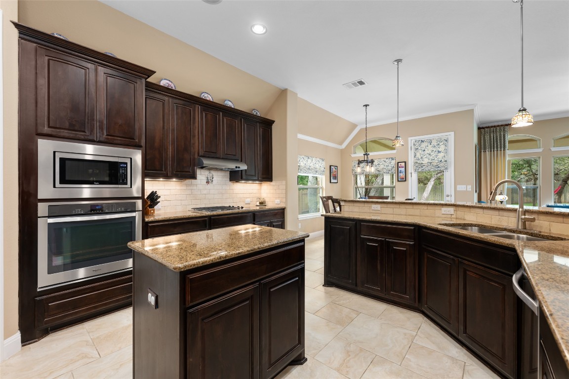 399 Whispering Wind Way Austin, TX 78737 - Photo 19 of 40 Kitchen featuring appliances with stainless steel finishes, under cabinet range hood, tasteful backsplash, plenty of natural light, and vaulted ceiling