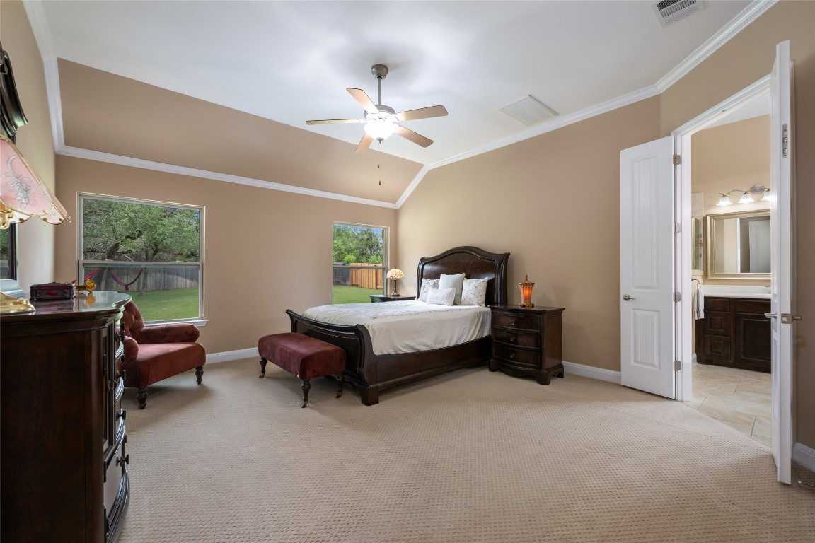 399 Whispering Wind Way Austin, TX 78737 - Photo 20 of 40 Bedroom with light carpet, crown molding, ensuite bathroom, lofted ceiling, and ceiling fan