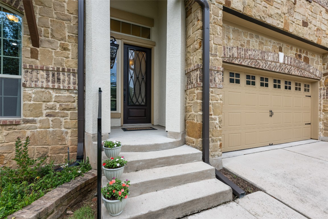 399 Whispering Wind Way Austin, TX 78737 - Photo 2 of 40 Entrance to property with stone siding, stucco siding, and driveway