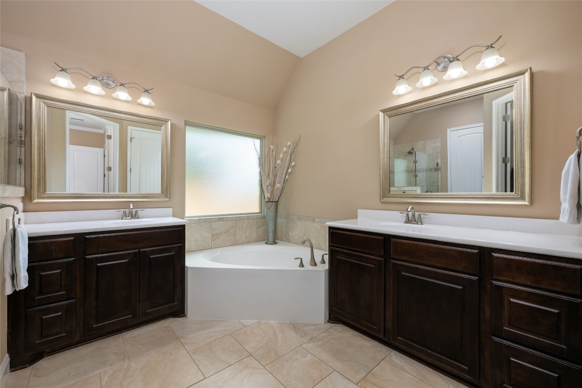 399 Whispering Wind Way Austin, TX 78737 - Photo 21 of 40 Bathroom with vaulted ceiling, a bath, two vanities, and tiled shower