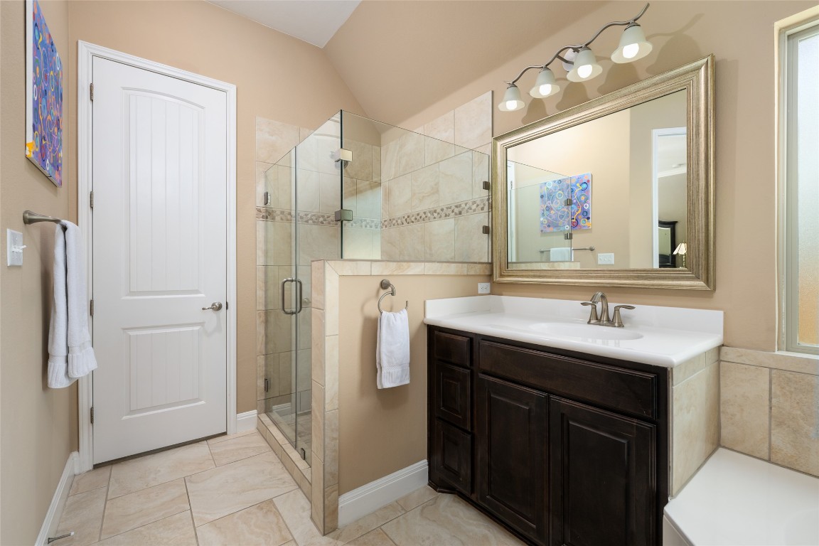 399 Whispering Wind Way Austin, TX 78737 - Photo 22 of 40 Full bath with a stall shower, vanity, and lofted ceiling