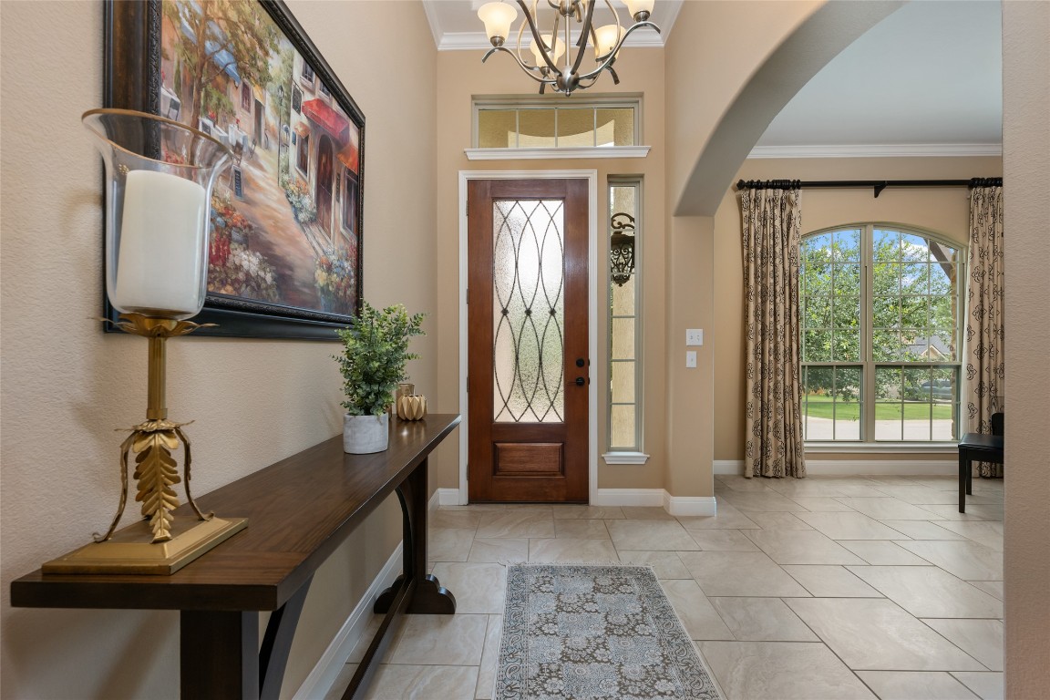 399 Whispering Wind Way Austin, TX 78737 - Photo 3 of 40 Entryway featuring arched walkways, ornamental molding, a chandelier, and marble look tile flooring