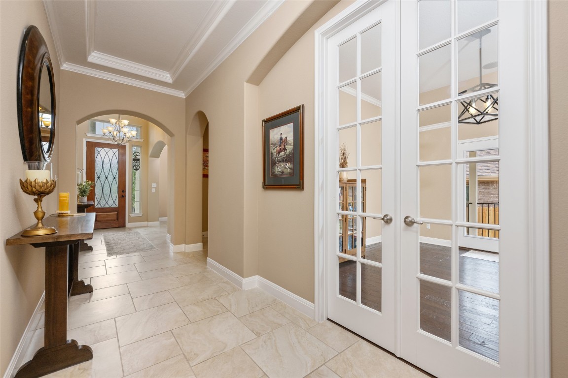 399 Whispering Wind Way Austin, TX 78737 - Photo 10 of 40 Entryway featuring arched walkways, ornamental molding, a chandelier, and french doors