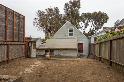 a view of a small house with wooden fence