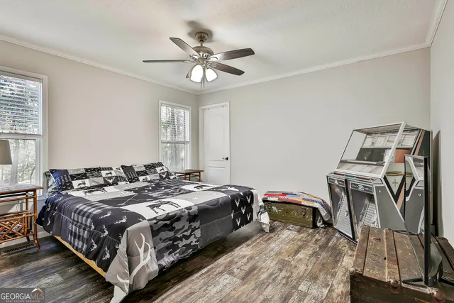 a bedroom with a bed a dresser and wooden floor