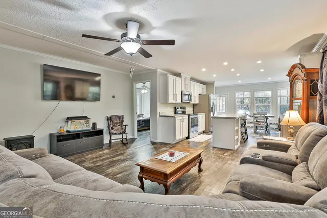 a living room with furniture kitchen view and a chandelier