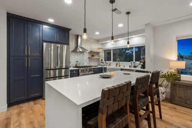 a large kitchen with a large counter top a sink stainless steel appliances and cabinets