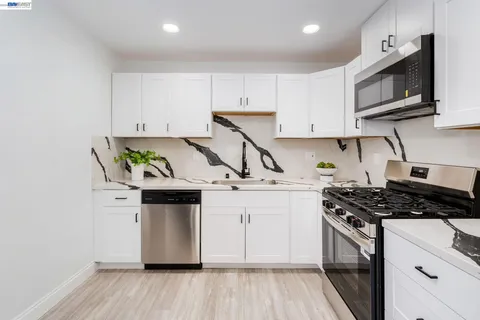 a kitchen with stainless steel appliances a white stove top oven a sink and cabinets