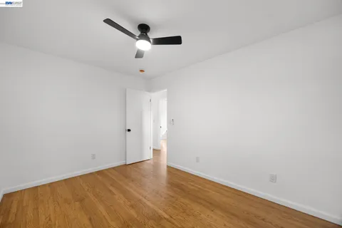 an empty room with wooden floor and ceiling fan
