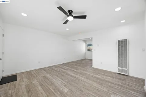 an empty room with wooden floor ceiling fan and windows