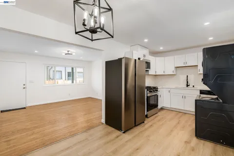 a kitchen with granite countertop a refrigerator a stove a microwave and white cabinets with wooden floor