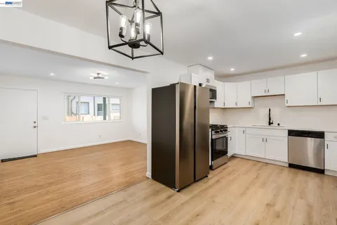 a kitchen with stainless steel appliances granite countertop a refrigerator a stove and white cabinets with wooden floor