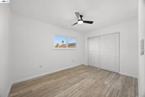 a view of empty room with wooden floor and fan