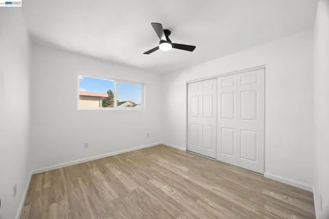 an empty room with wooden floor ceiling fan and windows