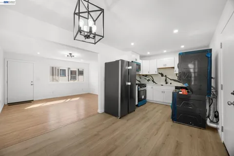 a kitchen with stainless steel appliances kitchen island granite countertop a refrigerator oven a sink dishwasher and a stove with wooden floor