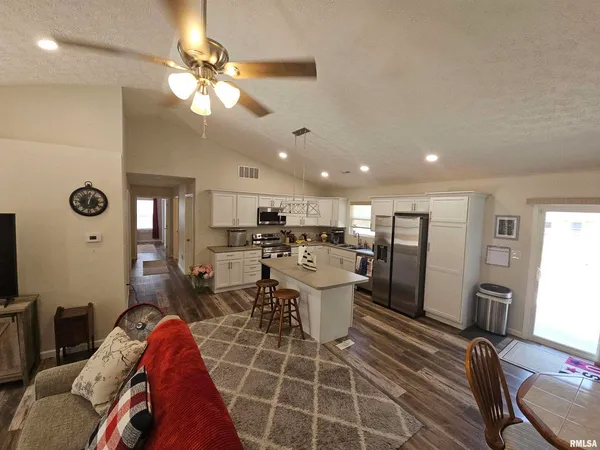 a living room with furniture a flat screen tv and kitchen view