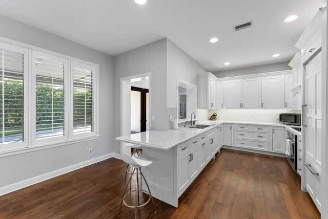 a large kitchen with cabinets wooden floor and stainless steel appliances