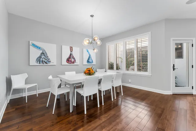 a dining room with wooden floor a chandelier a wooden table and chairs