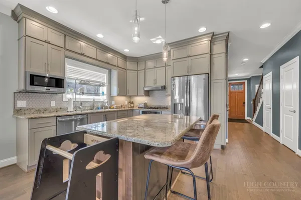 a open dining room with stainless steel appliances kitchen island granite countertop a dining table chairs and a refrigerator